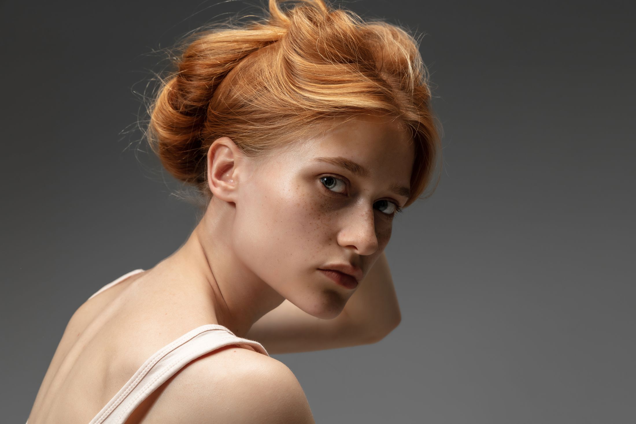 Red-haired young woman looking over her shoulder.